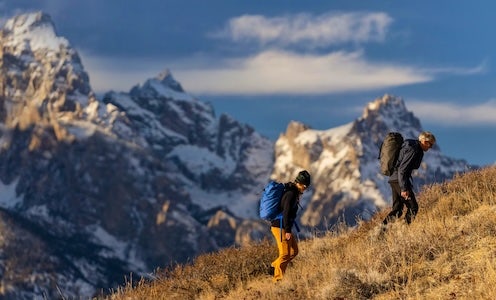 två personer vandrar och i bakgrunden ser man stora snöiga berg