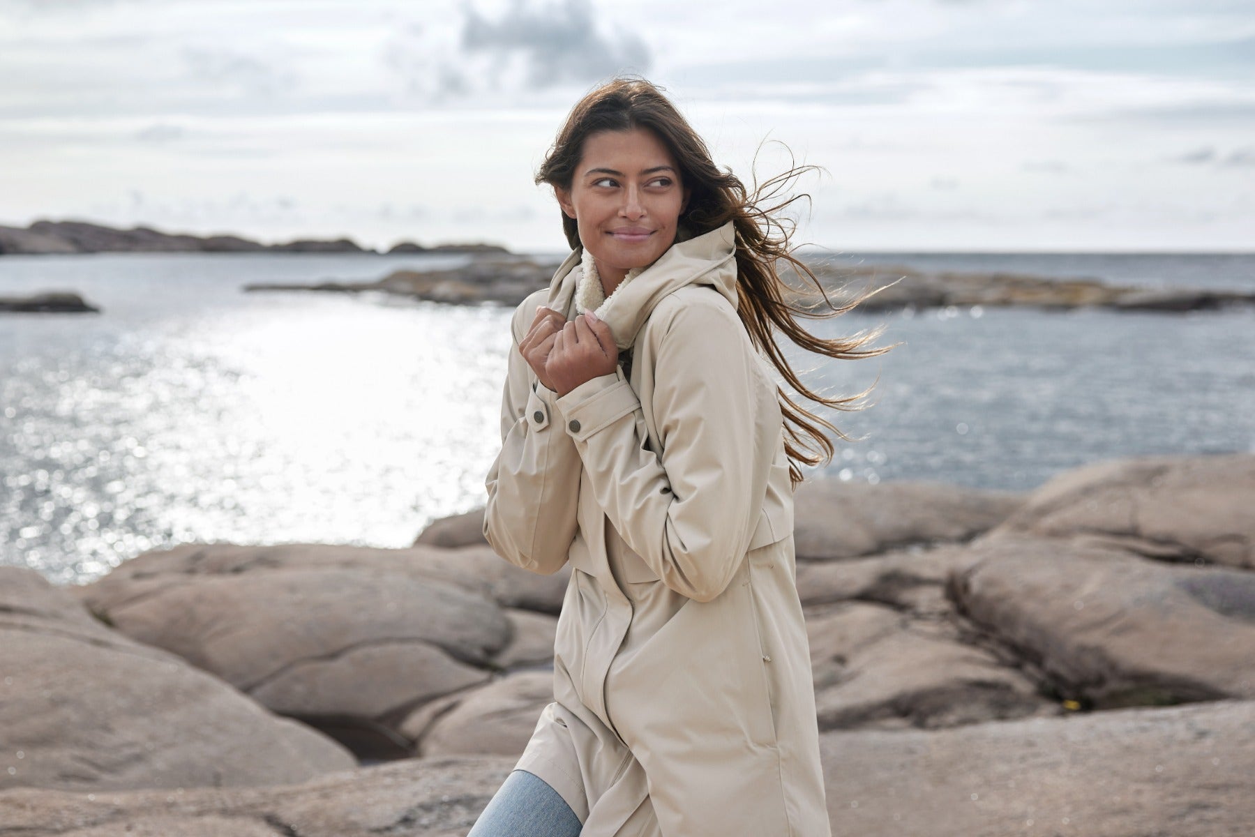 kvinna i regnjacka med havet i bakgrunden