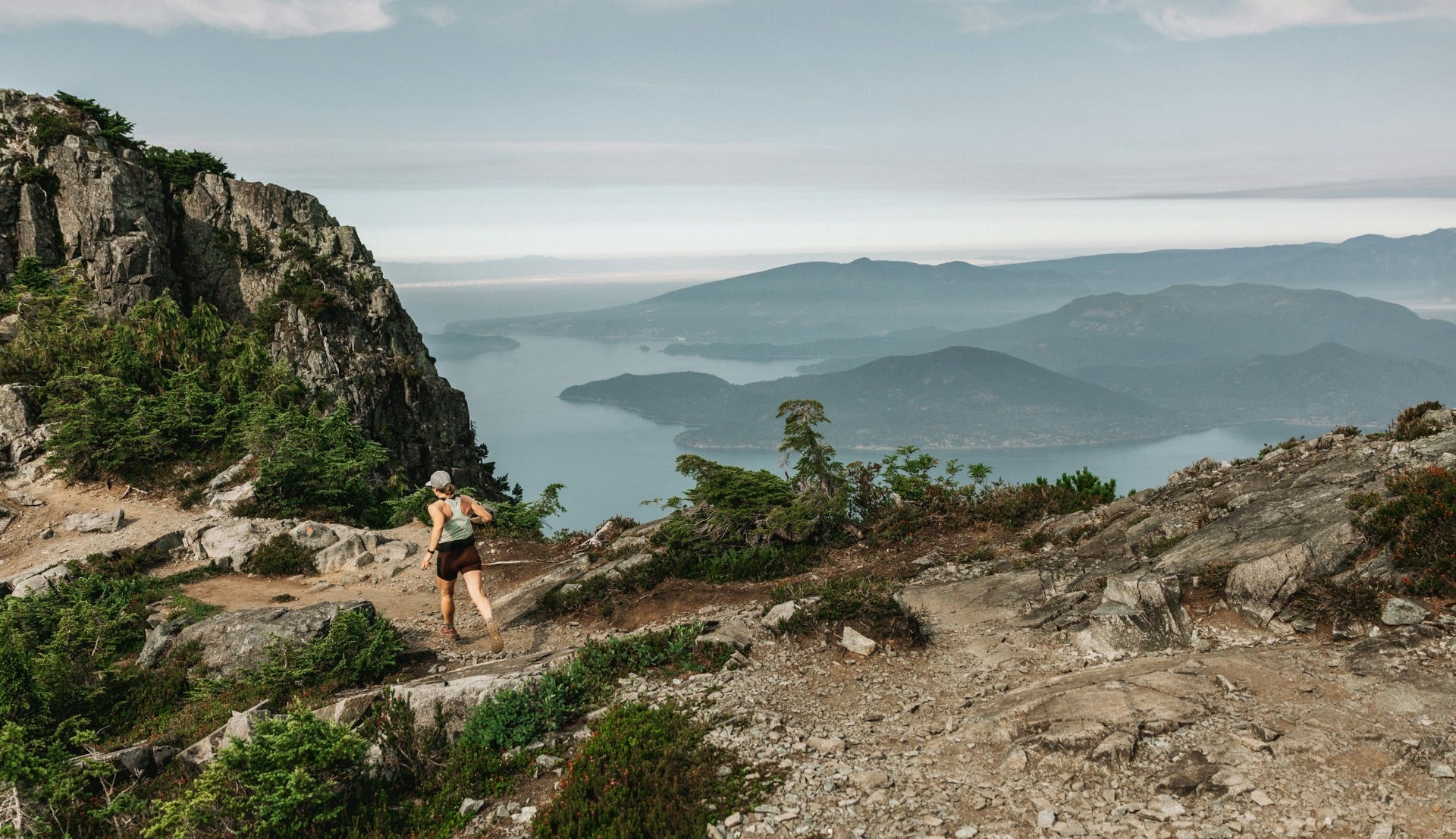 kvinna som springer på en stig högt upp på ett berg